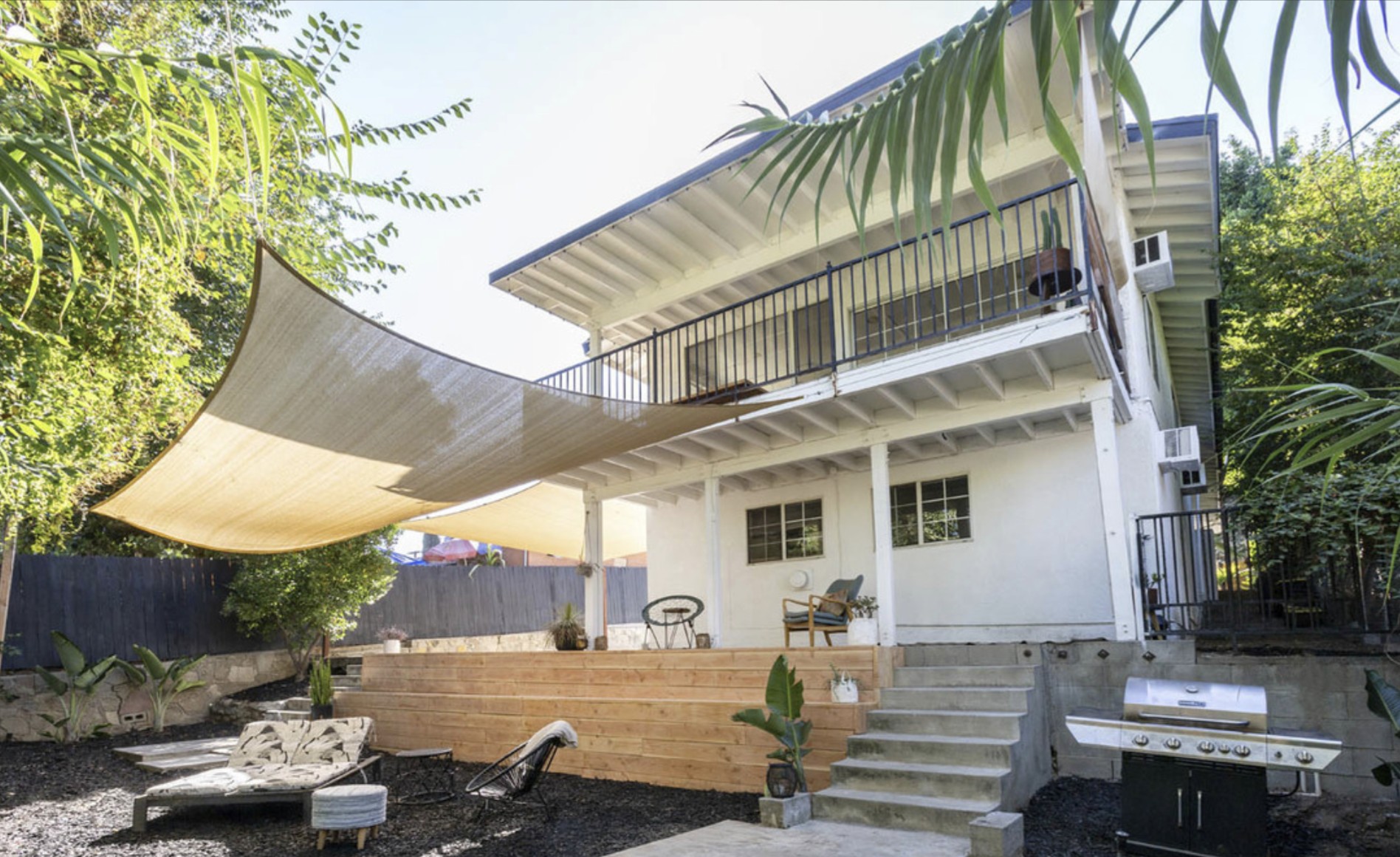 Backyard with shade sails, new wood steps, and plants